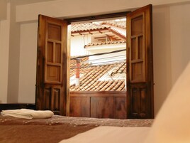 A room with a wooden door leading to a balcony with a tiled roof.