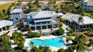A large resort with a central pool, multiple guest villas, and a well-maintained tropical garden.