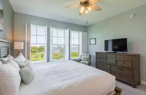 A bedroom with a large bed, a dresser, a television, and a ceiling fan. - Sunset Escape - Incredible Waterfront Condo Near Beautiful Anna Maria Island! (Bradenton)