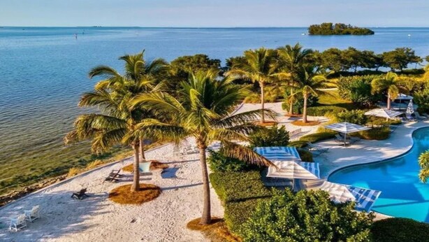 A resort with a pool, palm trees, and a beach area.