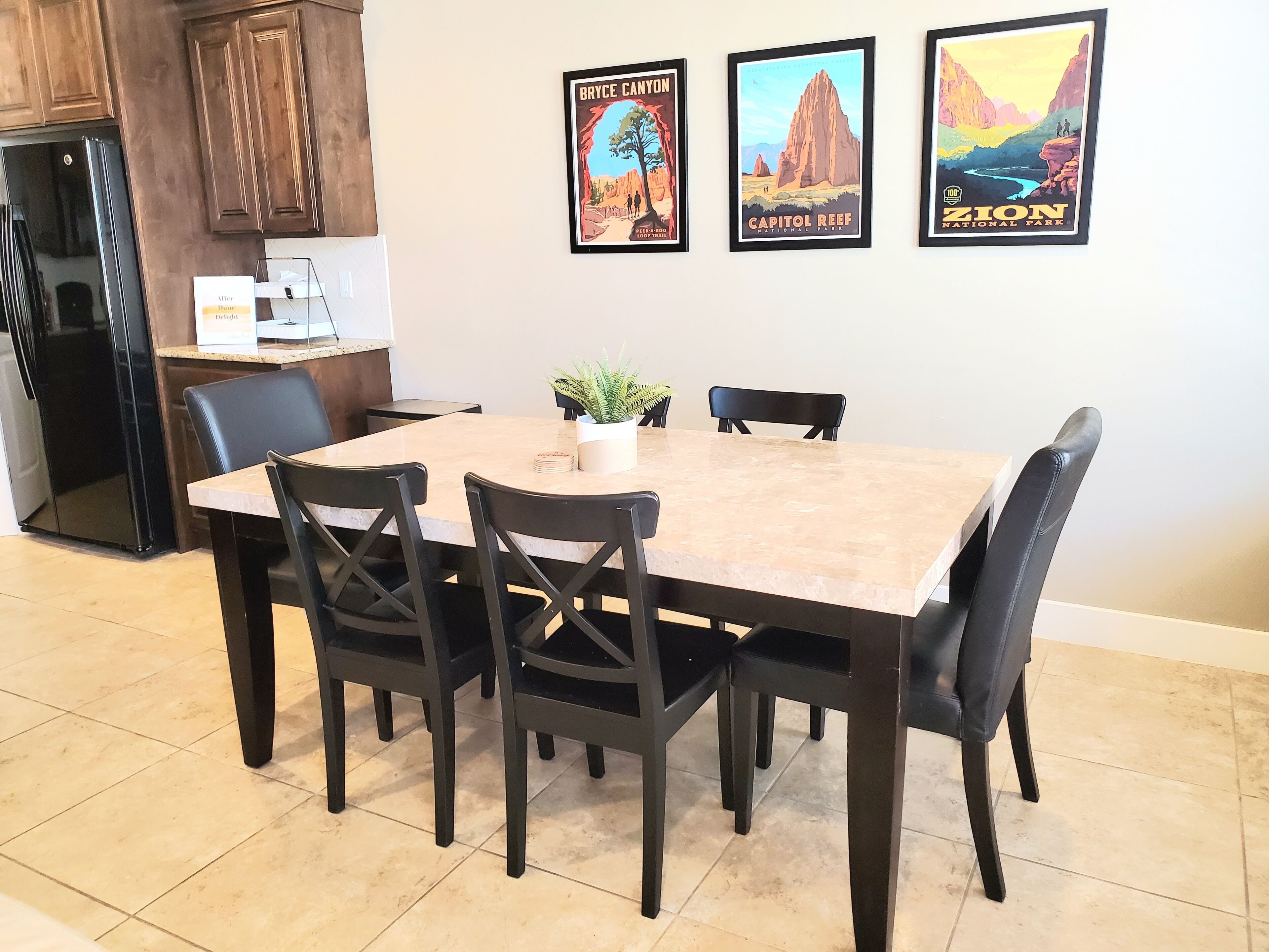 A dining area with a marble table, four chairs, and a potted plant.