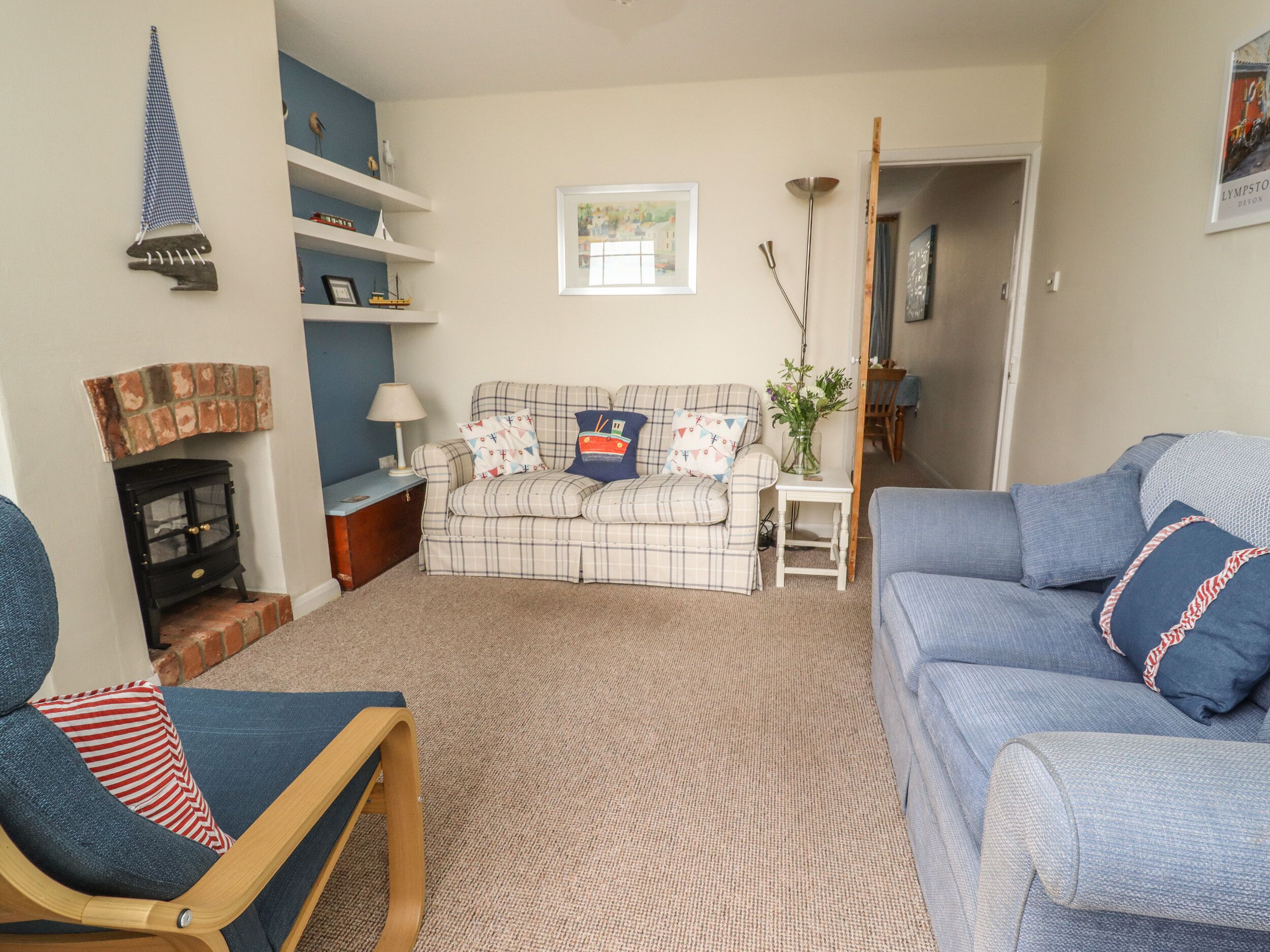 A living room with a plaid sofa, a blue armchair, a fireplace, and a bookshelf.