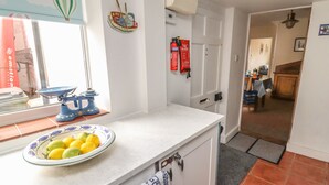 Una cucina con un piano di lavoro bianco, una ciotola di limoni, una bilancia blu e un estintore sulla parete.