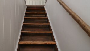 Una scala in legno con pareti bianche e una finestra in cima.