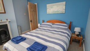 Una camera da letto con un letto, un comodino, una lampada, un quadro, una porta e un camino.