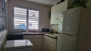 A compact kitchen with a refrigerator, microwave, and a small stove. - Private Beachfront House (Cabo Rojo)