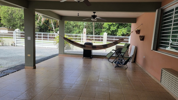 A covered outdoor area with a hammock, ceiling fans, and a view of greenery through the open sides. - Private Beachfront House (Cabo Rojo)