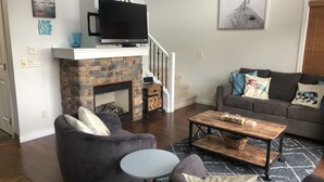 Un salon avec une cheminée, un téléviseur, un canapé et une table basse.