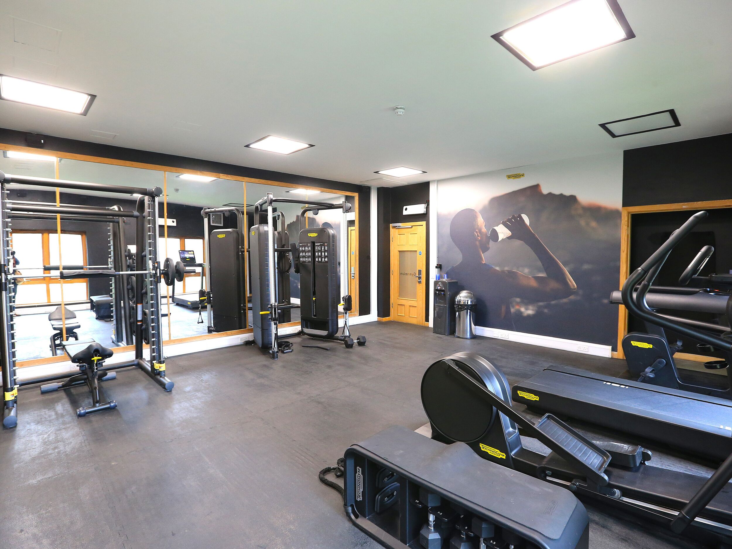 A gym with exercise equipment, mirrors, and a treadmill.