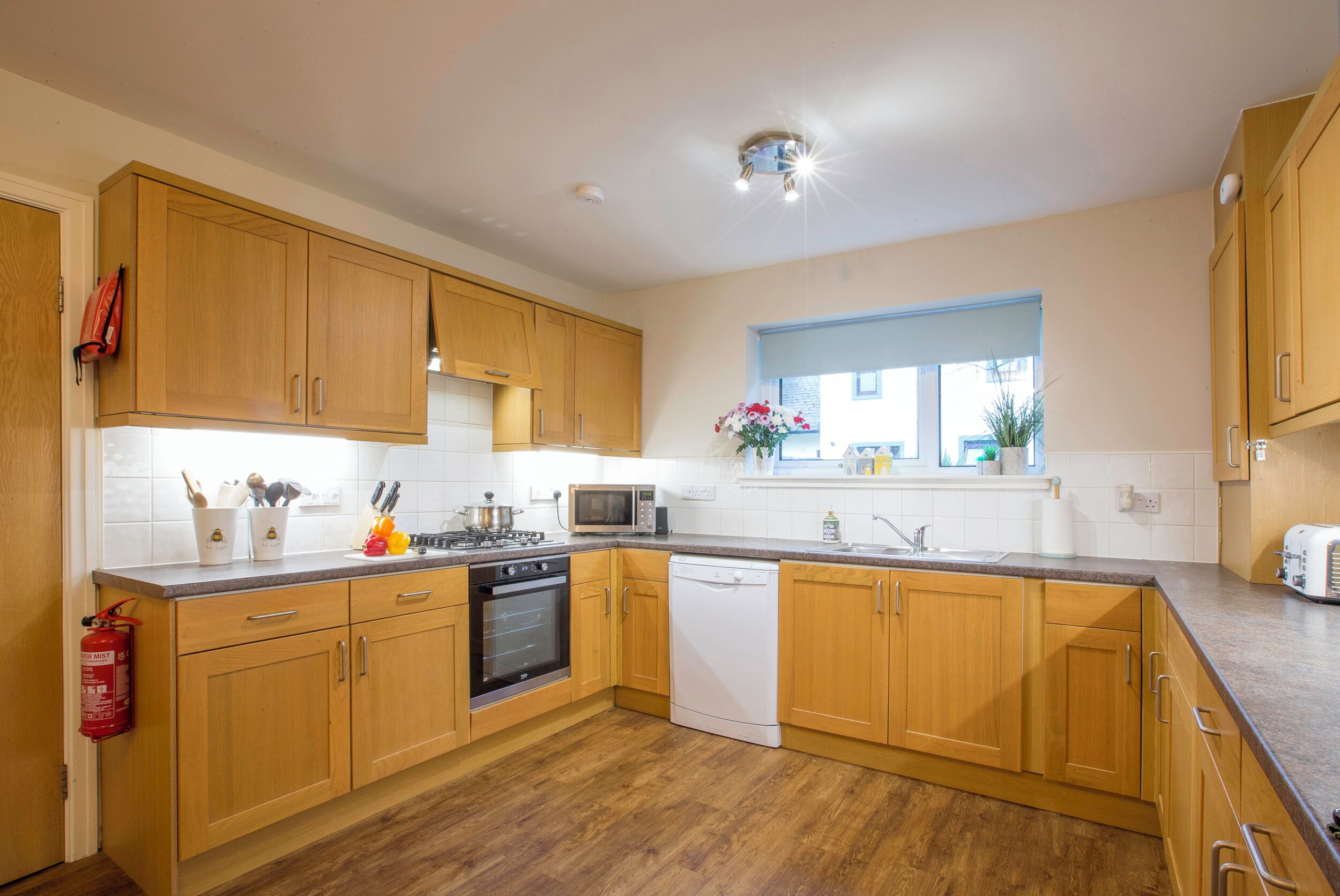 A modern kitchen with wooden cabinets, a microwave, stove, and dishwasher.