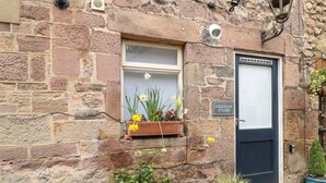 A stone building with a window displaying daffodils and a door labeled "Kirkham Studio". - Kirkham House (Matlock)