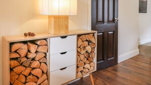 A wooden console table with a lamp and a stack of firewood drawers. - Kirkham House (Matlock)