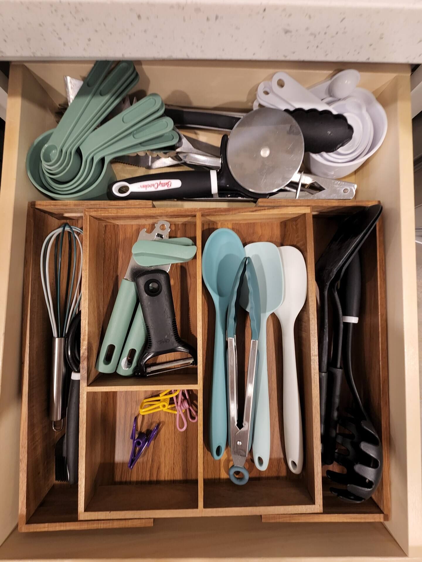 A kitchen drawer with various utensils and kitchen tools organized in compartments.