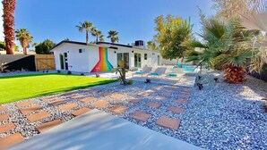 A modern house with a colorful mural, a swimming pool, and a well-maintained garden.
