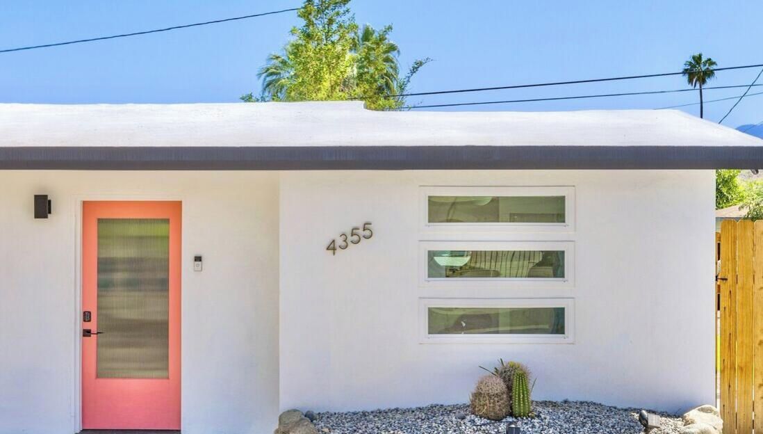 Un edificio moderno con facciata bianca, una porta rossa e il numero 4355 sulla parete.