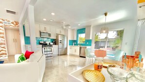 A modern kitchen with white cabinets, a stainless steel refrigerator, and a blue backsplash.