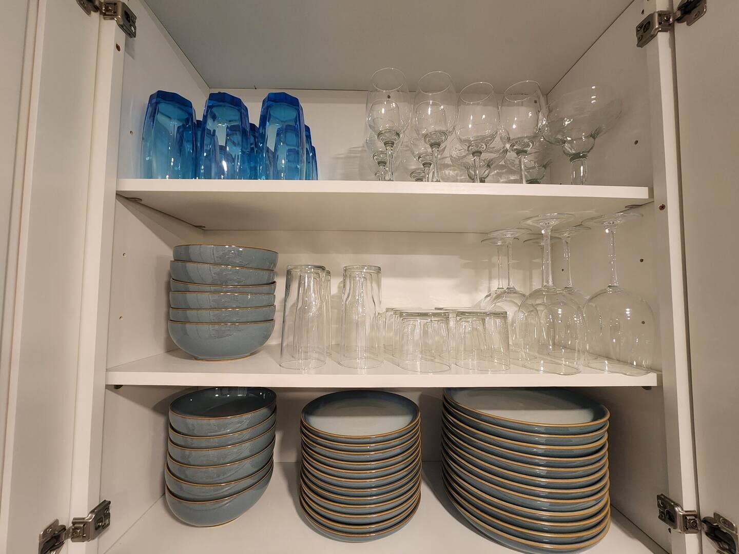 Un meuble de rangement doté d’étagères où sont rangés divers objets en verre et bols.