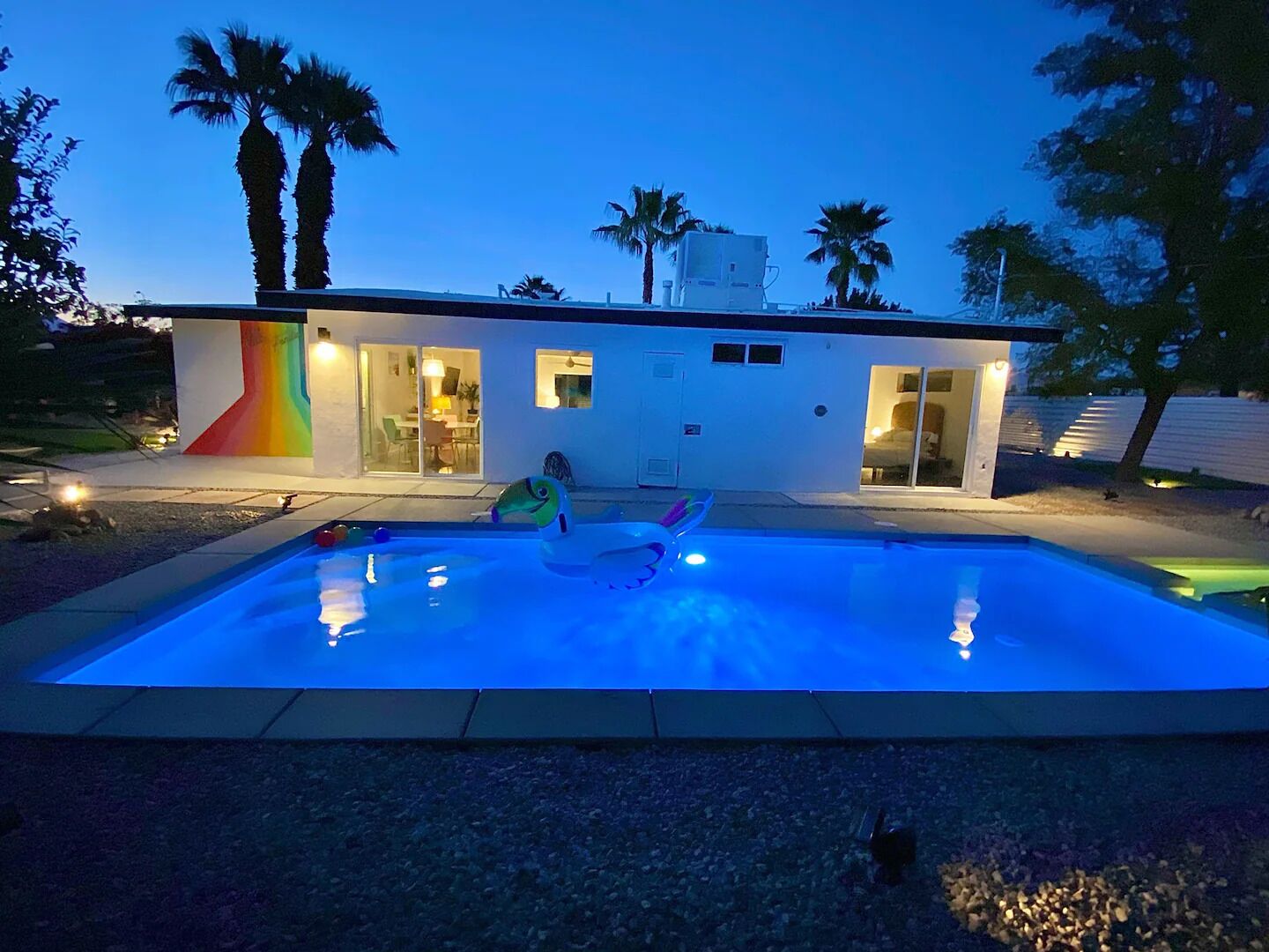 Una casa moderna con piscina, un muro de colores del arcoíris y palmeras.
