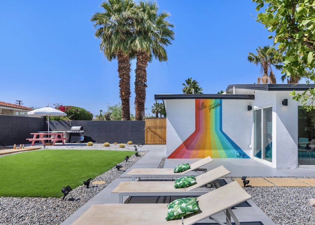 Un espacio exterior moderno con piscina, sillones de descanso y un mural colorido.
