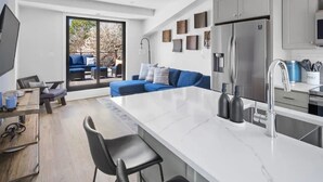 Una cucina moderna con una grande isola, mobili grigi e un frigorifero in acciaio inossidabile.