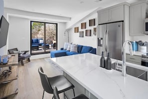 Una cocina moderna con una isla grande, armarios grises y un refrigerador de acero inoxidable.