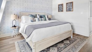 Una camera da letto con un letto, due comodini, un tappeto decorato e una parete con carta da parati geometrica.