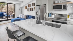 Una cucina moderna con una grande isola, elettrodomestici in acciaio inossidabile e un'area salotto con un divano blu.