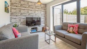 Ein modernes Wohnzimmer mit einer Steinwand, zwei grauen Sofas, einem Couchtisch und einem Flachbildfernseher.
