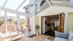 Un salón amplio con un gran ventanal, un comedor y una cocina visible a través de una puerta abierta.