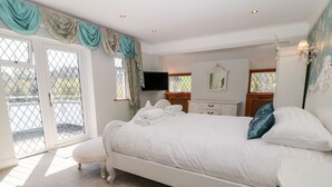 Un dormitorio con una cama grande, un aparador, un televisor y una ventana con cortinas.