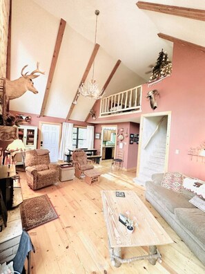 A spacious living room with high ceilings, wooden beams, a chandelier, and rustic decor including mounted animal heads. - Cabin right next to Burro St. in Cloudcroft (Cloudcroft)