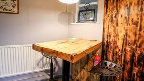 A kitchen with a wooden table, a hanging light, a window with a view, and a fire extinguisher. - Llys-yr-onnen (Carmarthen)
