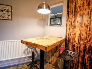 Una cocina con una mesa de madera, una lámpara colgante, un ventanal con vistas y un extintor.