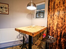 Una cocina con una mesa de madera, una lámpara colgante, un ventanal con vistas y un extintor.