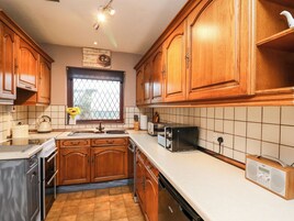Una cocina con armarios de madera, una ventana con vistas, un tostador y un radio.