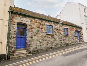 A stone building with a blue door and windows, a visible chimney, and a road with double yellow lines. - Llys-yr-onnen (Carmarthen)