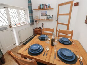 Un coin repas avec une table en bois dressée pour quatre personnes, des assiettes bleues et des verres à vin.