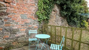 A brick wall with a metal table and chairs, a stone wall, and a green fence. - Llys-yr-onnen (Carmarthen)