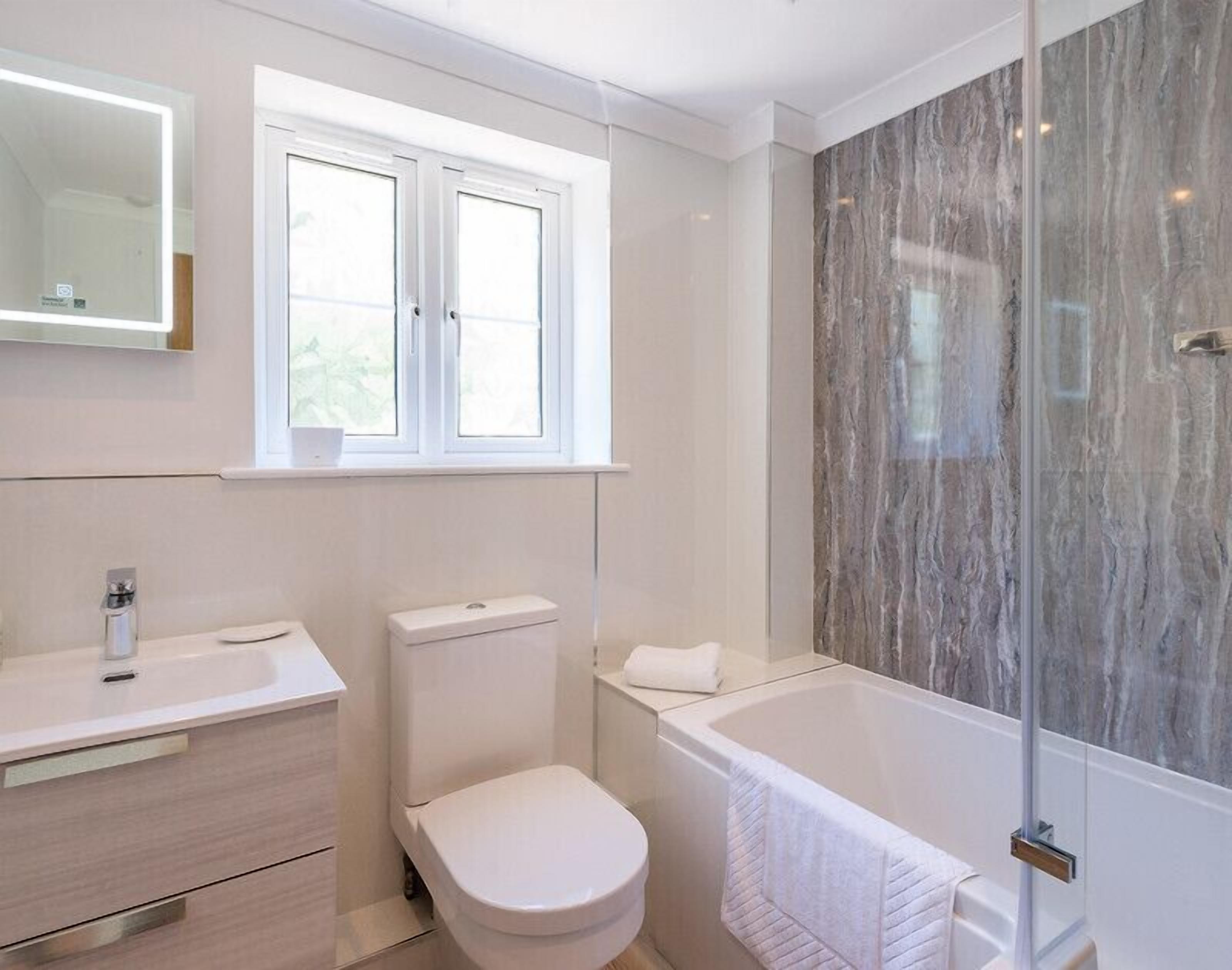 A modern bathroom with a toilet, sink, and bathtub.