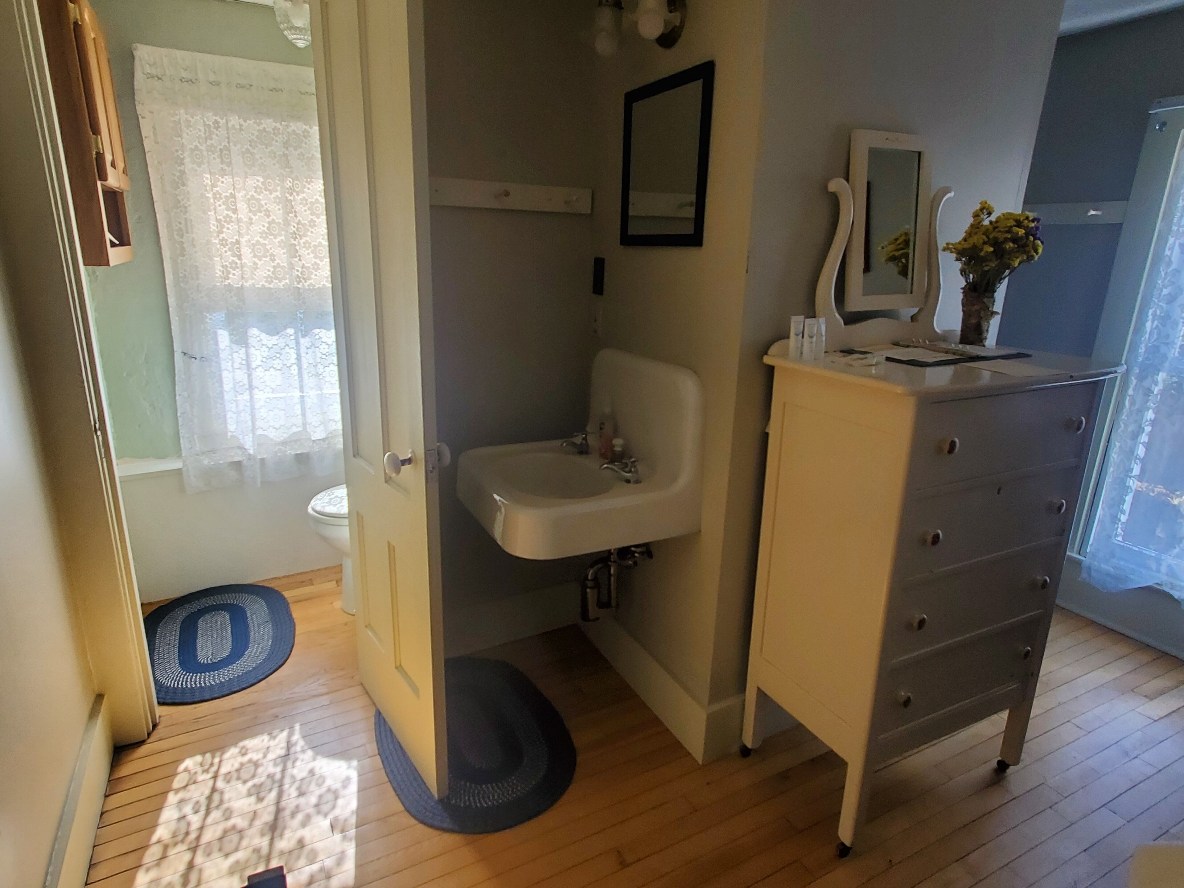 A bathroom with a sink, mirror, and a dresser.