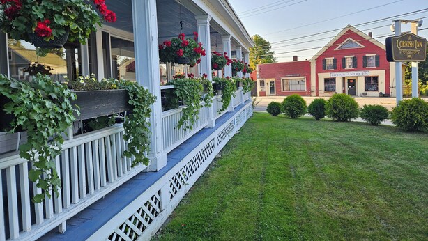 A porch with hanging flower baskets and a sign for The Cornish Inn. - The Cornish Inn (Cornish)