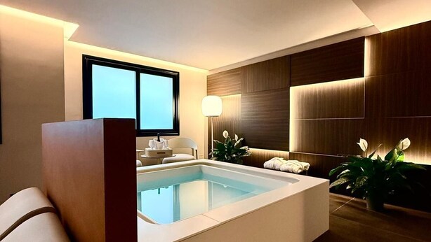 A modern bathroom with a large bathtub, a mirror, and a window. - Ollen apartments (Catania)