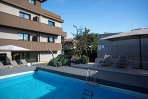 Relax by the pool surrounded by lounge chairs and umbrellas, with stunning views of the surrounding area.