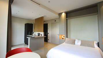 Une chambre d’hôtel moderne comprenant un lit, une petite kitchenette, un coin repas et une salle de bain séparée.