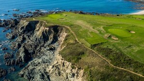 En kystgolfbane med en klippefyldt kystlinje, en sandstrand og frit udsyn til havet.