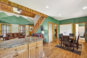 A spacious kitchen with a wooden island, a dining area with a table and chairs, and a staircase leading to another level.