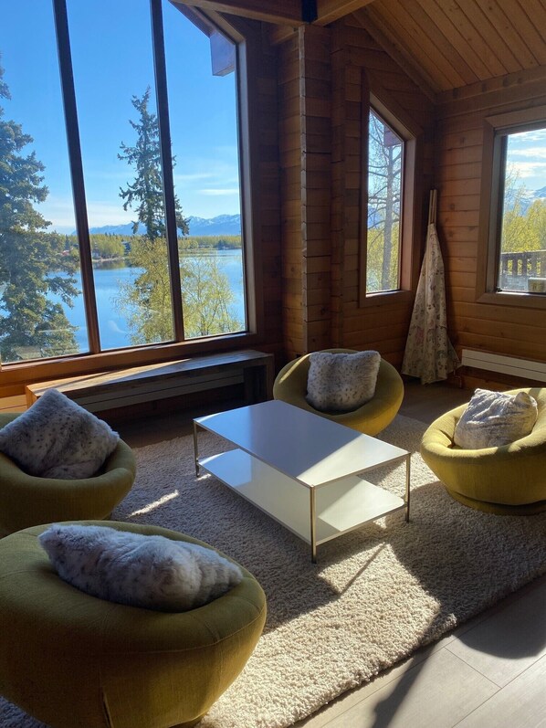 Relax in a serene space with a seating area featuring two armchairs and a coffee table, offering a view of the lake and surrounding trees.