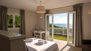 A bedroom with a bed, a desk, and a view of the sea. - Petite Grenade - View, sea access, infinity pool and tennis court (Le Vauclin)