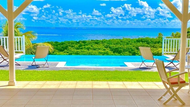 A covered outdoor area with a pool, chairs, and a view of the ocean. - Petite Grenade - View, sea access, infinity pool and tennis court (Le Vauclin)