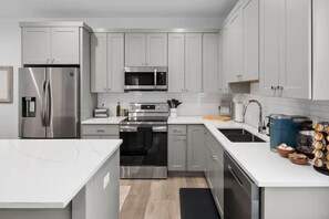 Una cocina moderna con electrodomésticos de acero inoxidable, armarios blancos y una isla central.